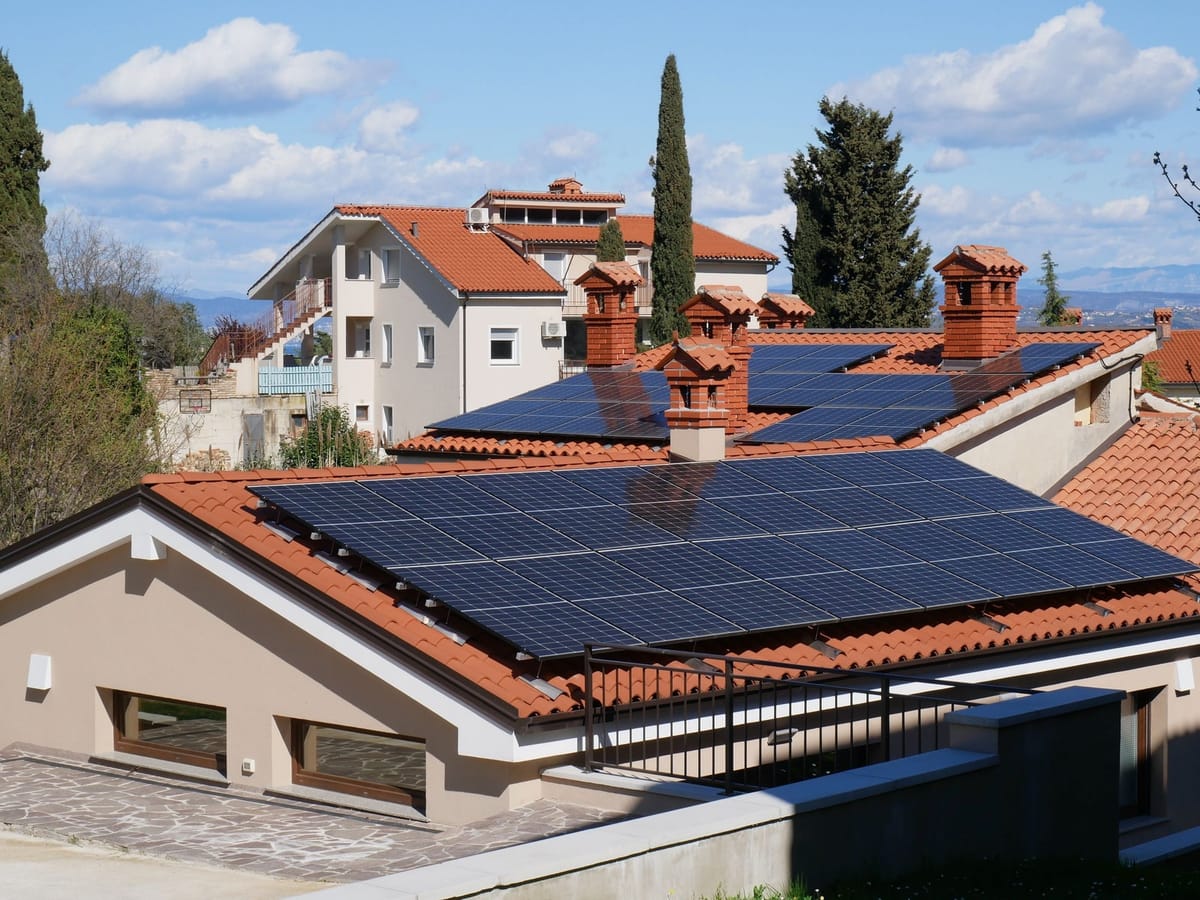 Kırmızı kiremitli ve bacalı müstakil evin çatısına kurulmuş güneş panelleri